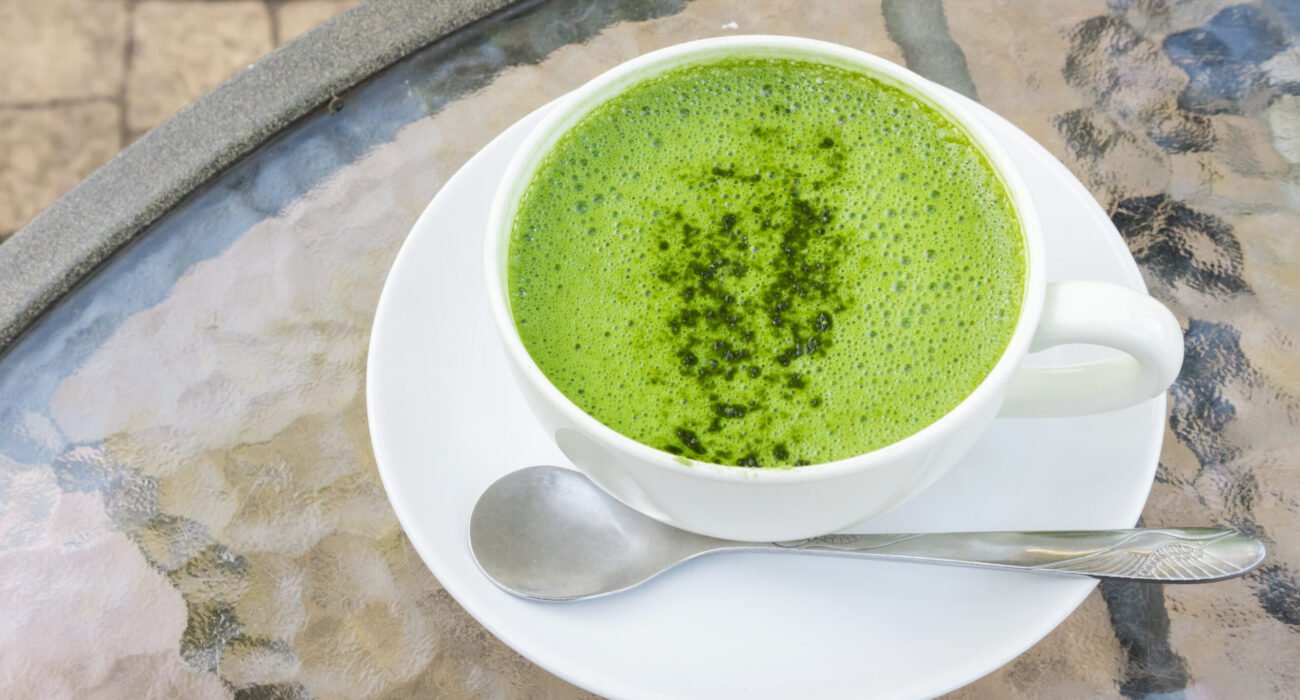 Closeup a cup of matcha latte or green tea on glass table background