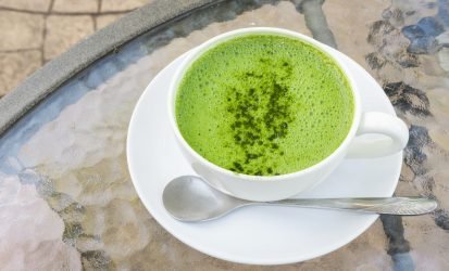 Closeup a cup of matcha latte or green tea on glass table background