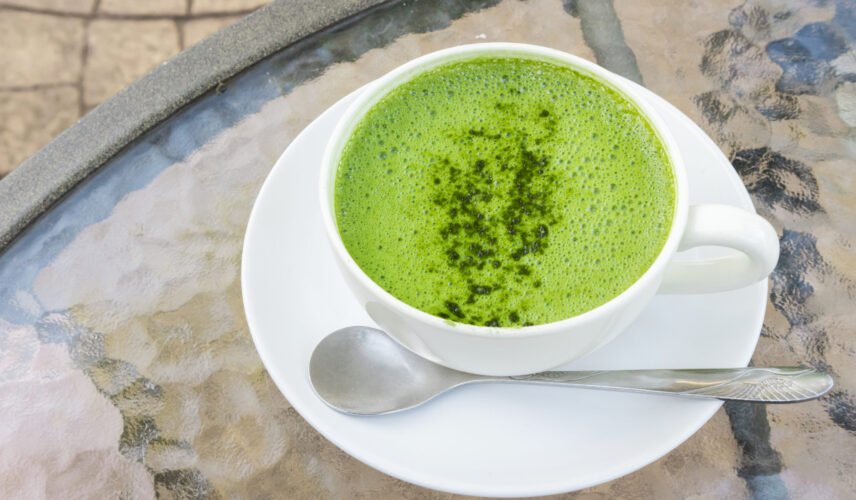 Closeup a cup of matcha latte or green tea on glass table background